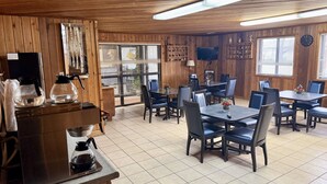 A restaurant with wooden walls, tiled flooring, and tables with chairs.