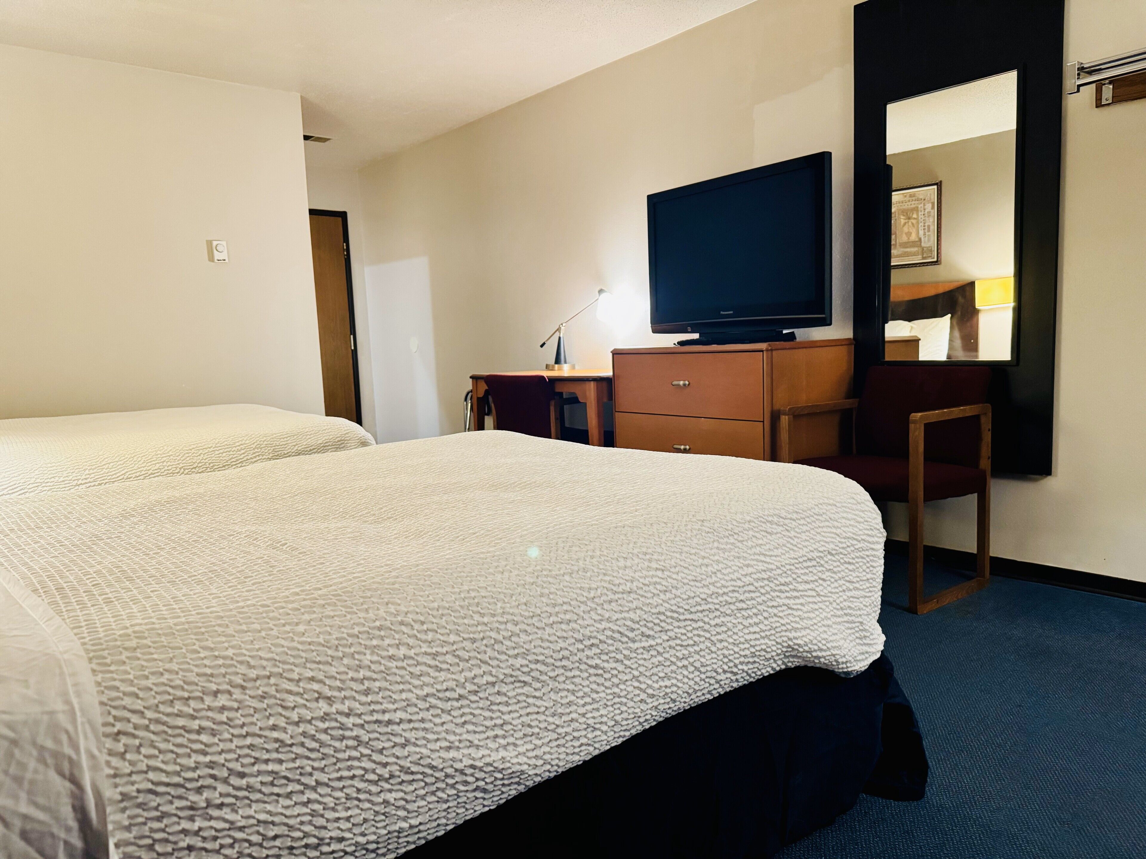 Una habitación de hotel con dos camas, televisión, escritorio y una silla.