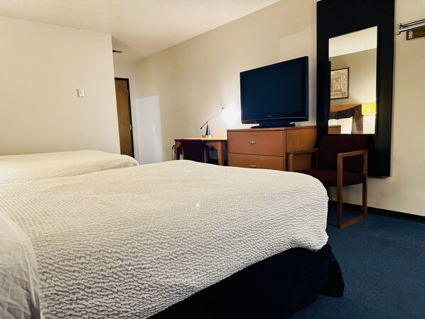 Une chambre d’hôtel avec deux lits, une télévision, un bureau et une chaise.