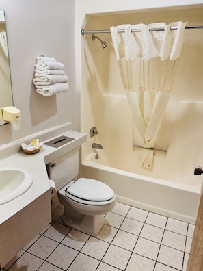 A bathroom with a toilet, sink, and bathtub. - Travel Inn (Watertown)