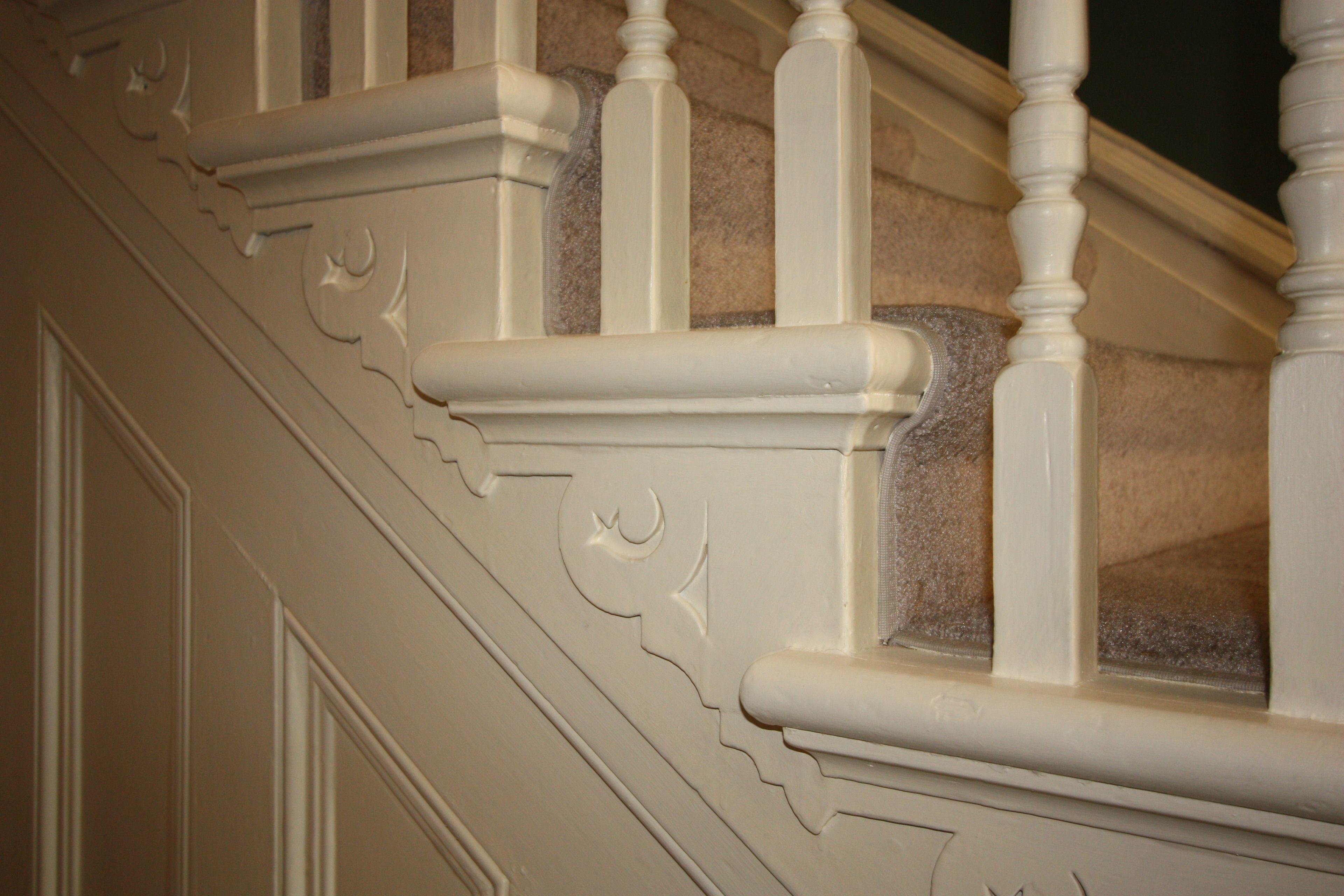 A close-up of a staircase with ornate white balusters and detailed molding.