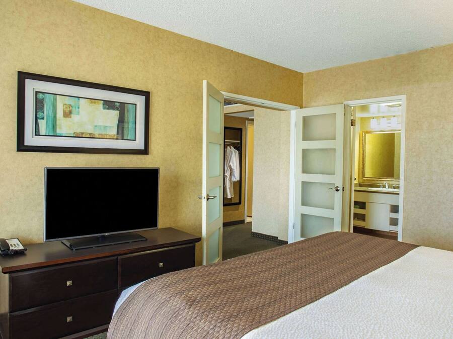 Una habitación de hotel con cama, televisión, cómoda, armario y baño.