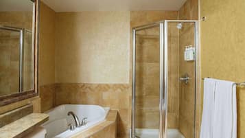 Un baño con bañera, ducha con mampara de vidrio y toallero.