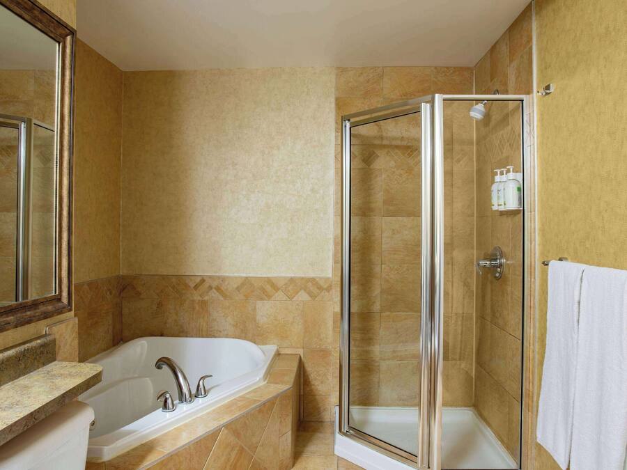 Un baño con bañera, ducha con mampara de vidrio y toallero.