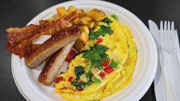 Un plato con tocino, salchichas y una tortilla adornada con verduras.