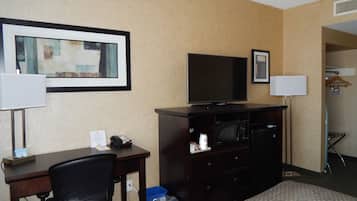 Habitación de hotel con cama, escritorio con silla, televisor, teléfono y un cuadro en la pared.