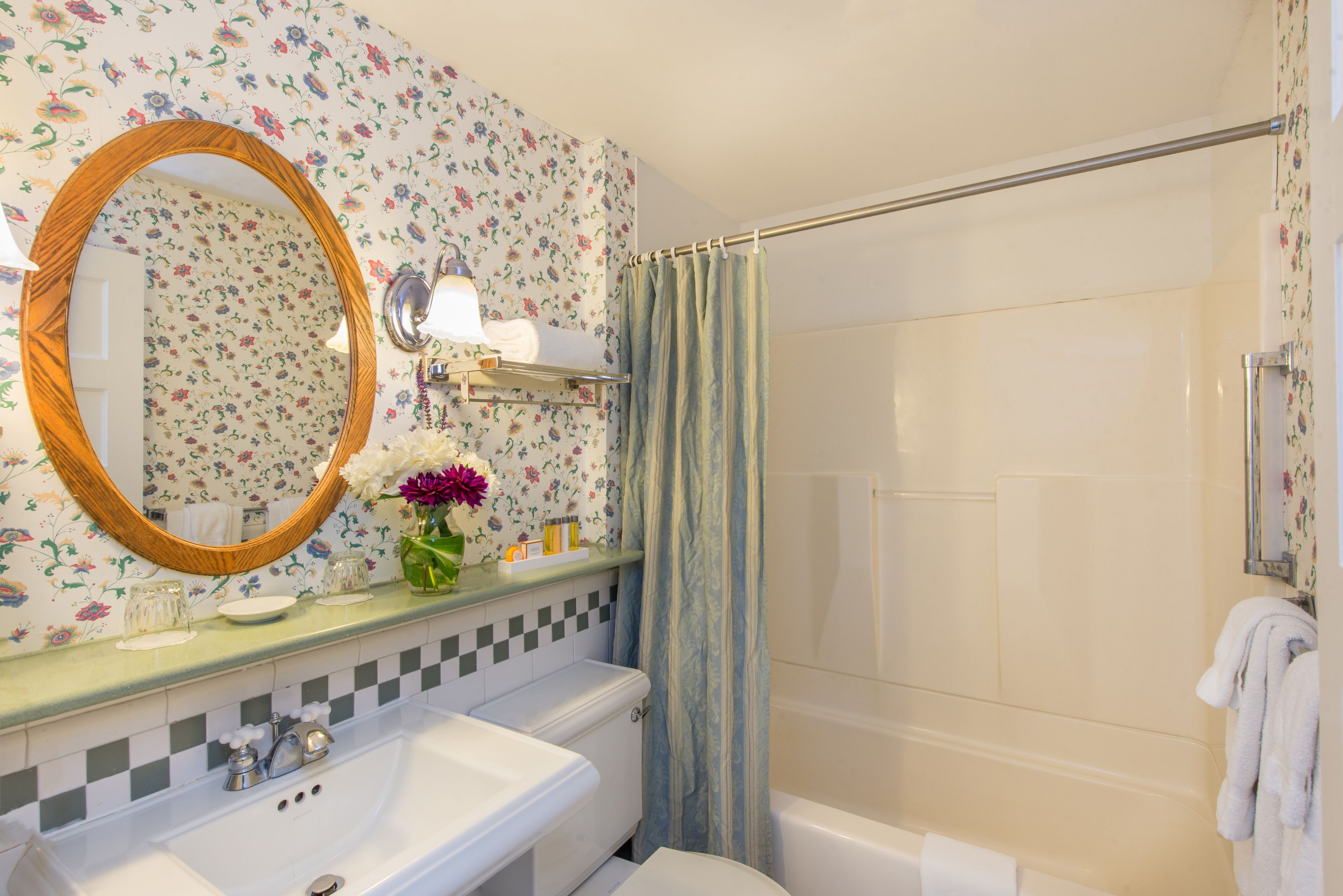 A bathroom with a sink, mirror, and shower curtain.