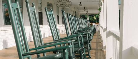 Una fila de sillas verdes en un porche con un cartel que dice 'Eagle Mountain House Veranda Cafe'.
