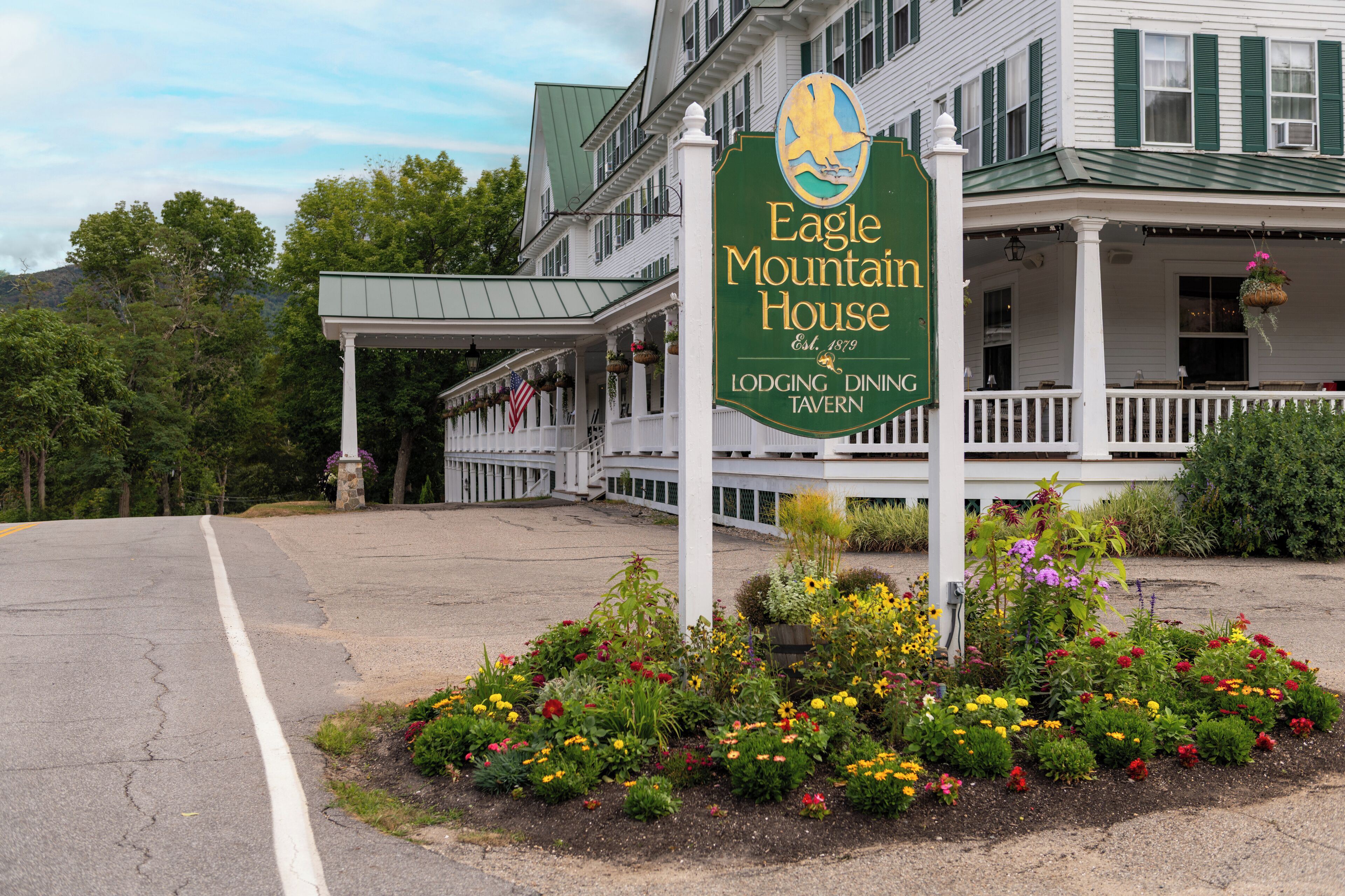 The exterior of the Eagle Mountain House, a lodging and dining establishment with a porch and hanging flower baskets.