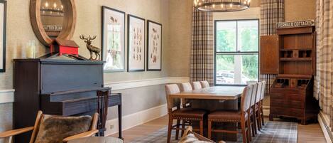 A dining area with a wooden table and chairs, a fireplace, framed pictures, and a sign reading "Fernald Cottages".