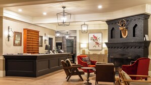 A modern kitchen with a central island, a fireplace with a deer head, and a seating area with red and brown chairs. - Eagle Mountain House & Golf Club (Jackson)