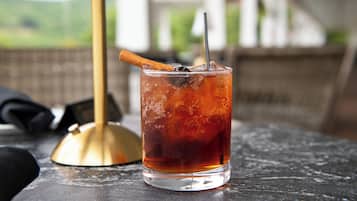 A glass of iced tea with a cinnamon stick and a straw on a table.