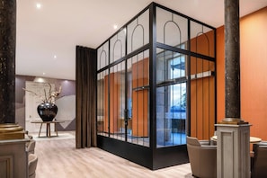 A modern lobby with a glass partition, wooden paneling, and a large vase on a table. - AC Hotel Palacio Universal by Marriott (Vigo)
