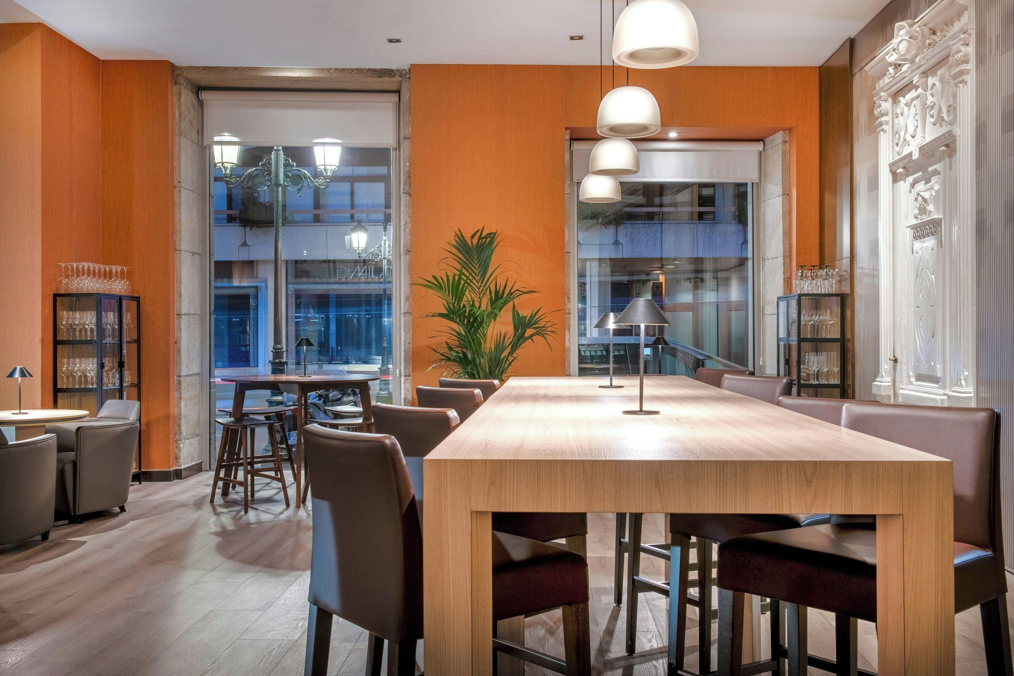 Una sala de conferencias moderna con una gran mesa de madera, asientos cómodos y ventanas amplias con vistas a la ciudad.