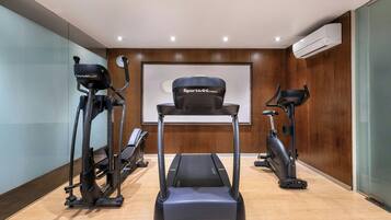Uma academia moderna com duas máquinas elípticas, uma esteira e uma bicicleta ergométrica.