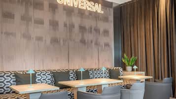 A modern lounge area with a sofa and tables, a wall with a vertical pattern, and a sign that reads 'UNIVERSAL'.