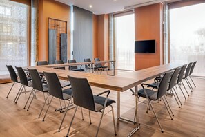 A conference room with a long table, multiple chairs, and a flat-screen TV. - AC Hotel Palacio Universal by Marriott (Vigo)