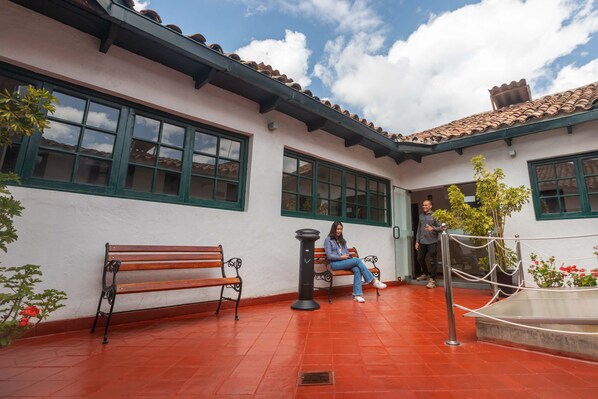 Un patio al aire libre con un banco, una planta en maceta y una barandilla de metal.
