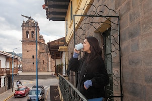 A person standing on a balcony with a view of a historic building in the background.