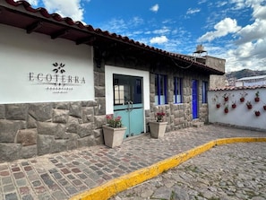 A building with a stone facade, a blue door, and potted plants. - Ecoterra Essentials San Blas (Cusco)