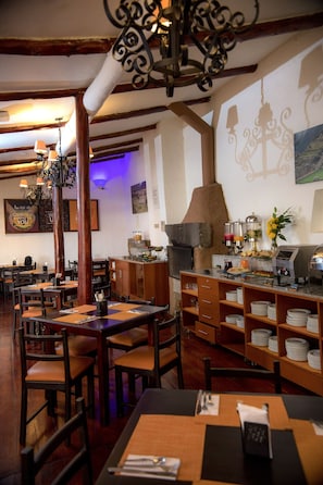 A restaurant interior with wooden tables, chairs, a bar area, and a pizza oven. - Ecoterra Essentials San Blas (Cusco)