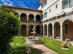 Un patio con una fuente, arcos y un edificio con balcones.