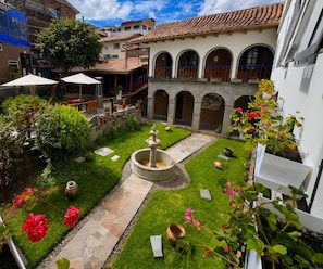 A courtyard with a fountain, potted plants, and a stone pathway. - Ecoterra Essentials San Blas (Cusco)