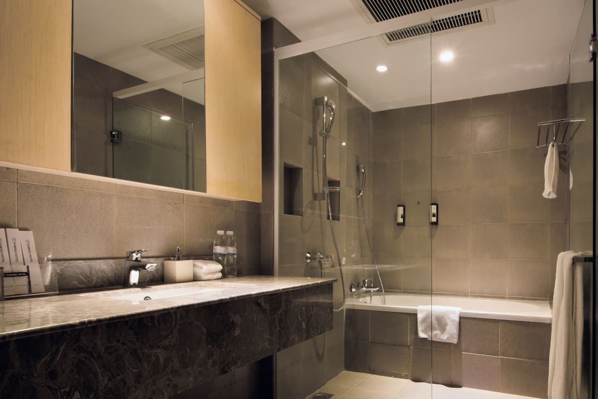 Un baño moderno con ducha de vidrio, encimera de mármol y un espejo grande.