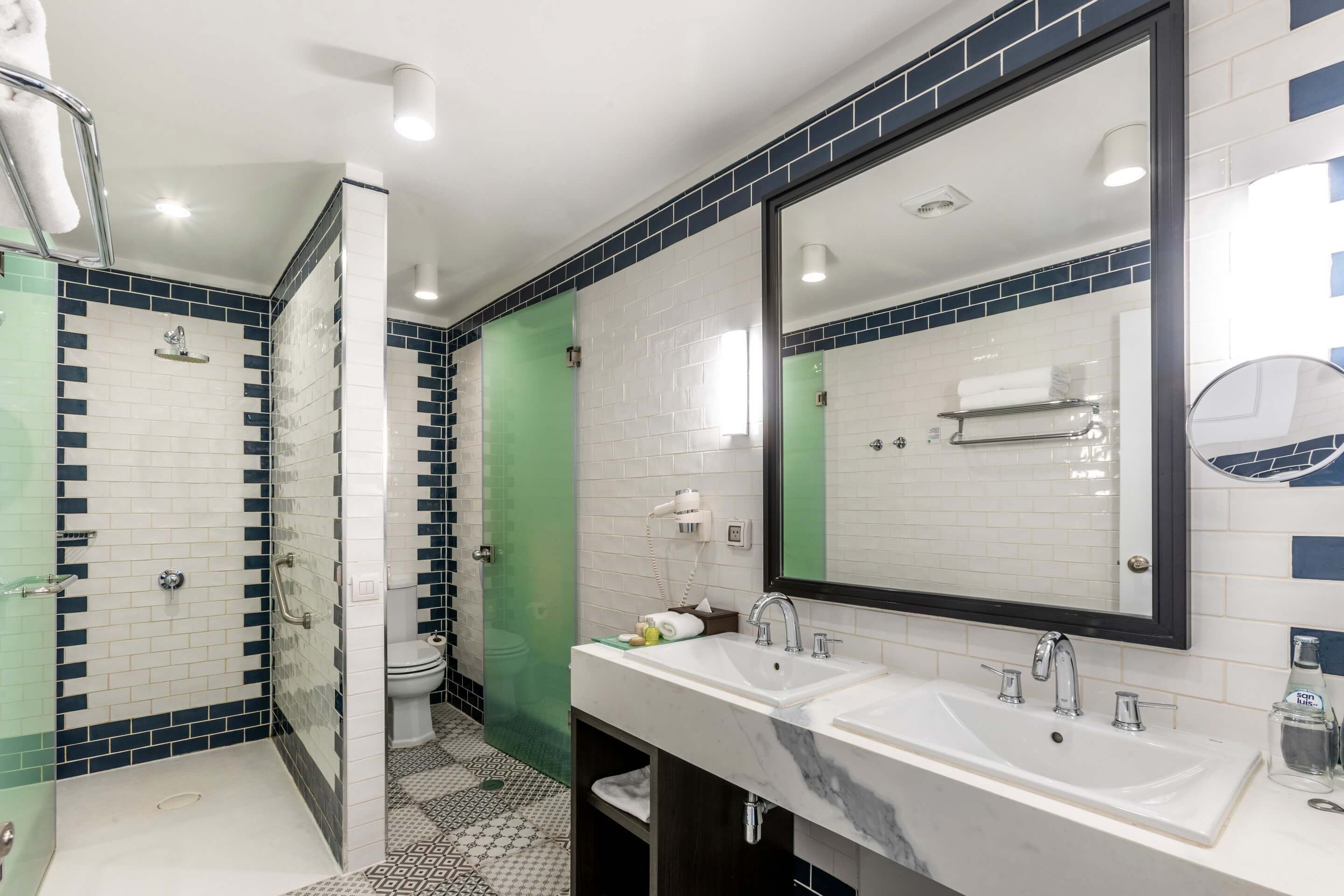 Une salle de bain moderne avec une douche à parois de verre, un meuble-lavabo à deux vasques et un grand miroir.
