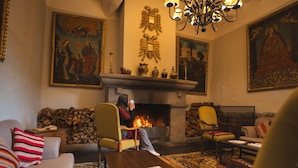 A cozy living room with a fireplace, comfortable seating, and decorative paintings. - Casa Andina Premium Cusco (Cusco)