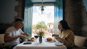 A dining table with plates of food, wine glasses, and a vase with flowers. - Casa Andina Premium Cusco (Cusco)