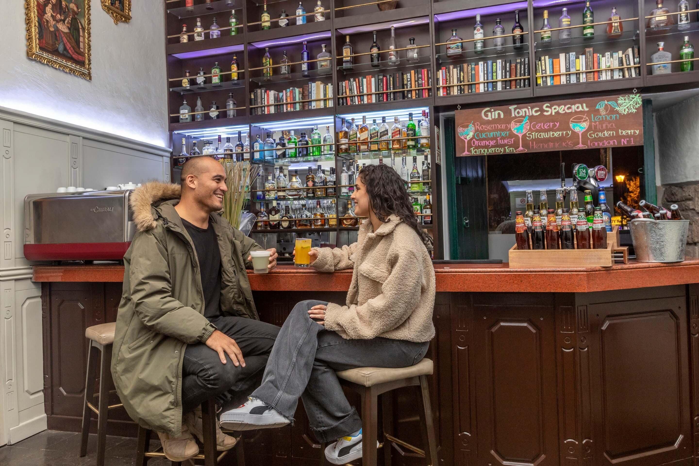 A bar area with a menu board listing gin tonic specials, shelves of liquor bottles, and a counter with bar tools.