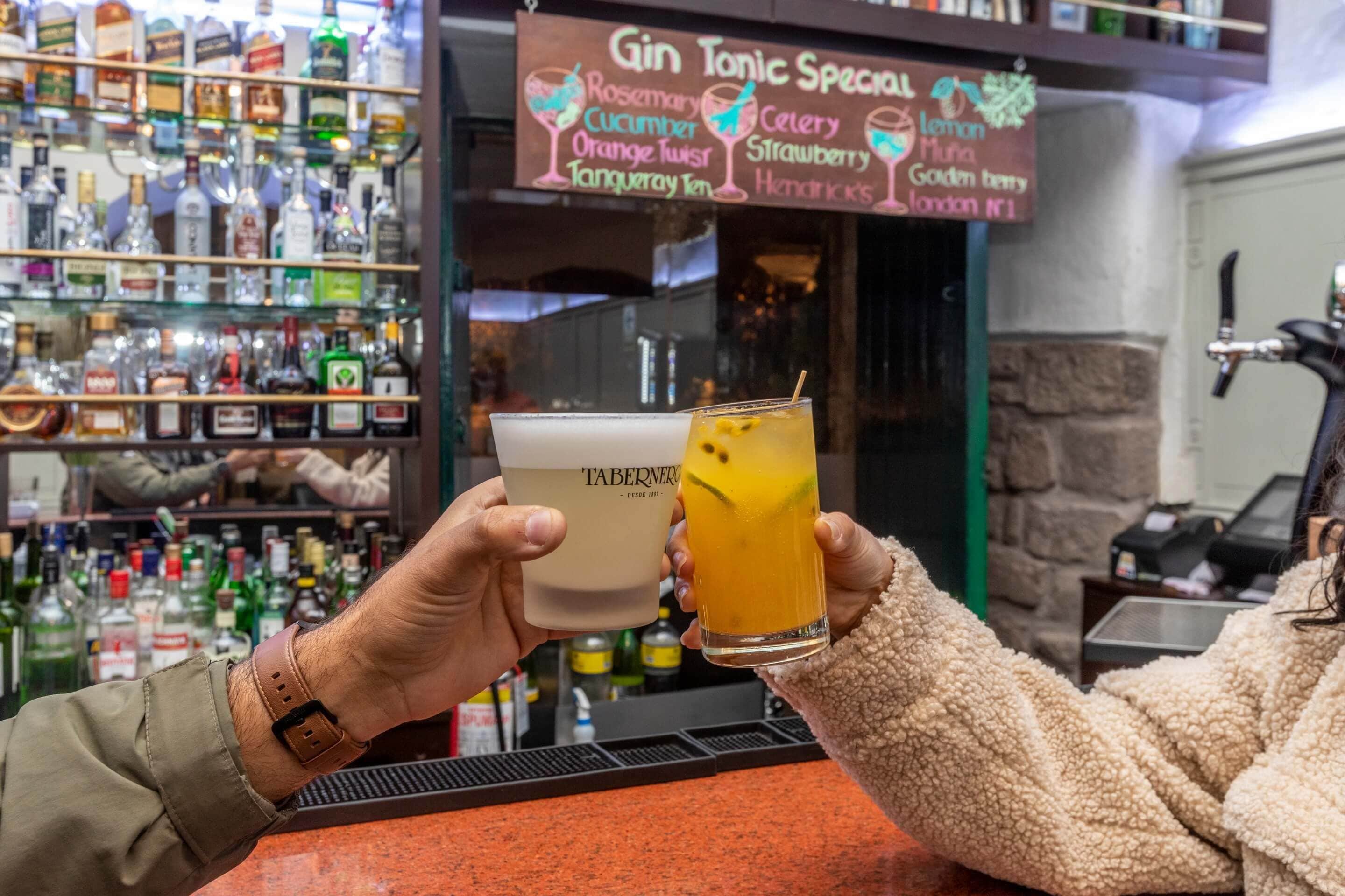 Eine Bar mit einer Auswahl an Spirituosenflaschen in Regalen und einer Tafel, die Gin Tonic Sonderangebote auflistet.