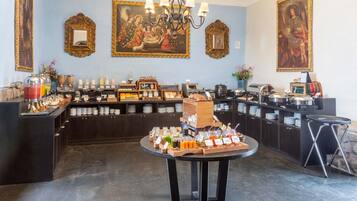 Uma mesa de buffet de café da manhã com diversos alimentos e bebidas.