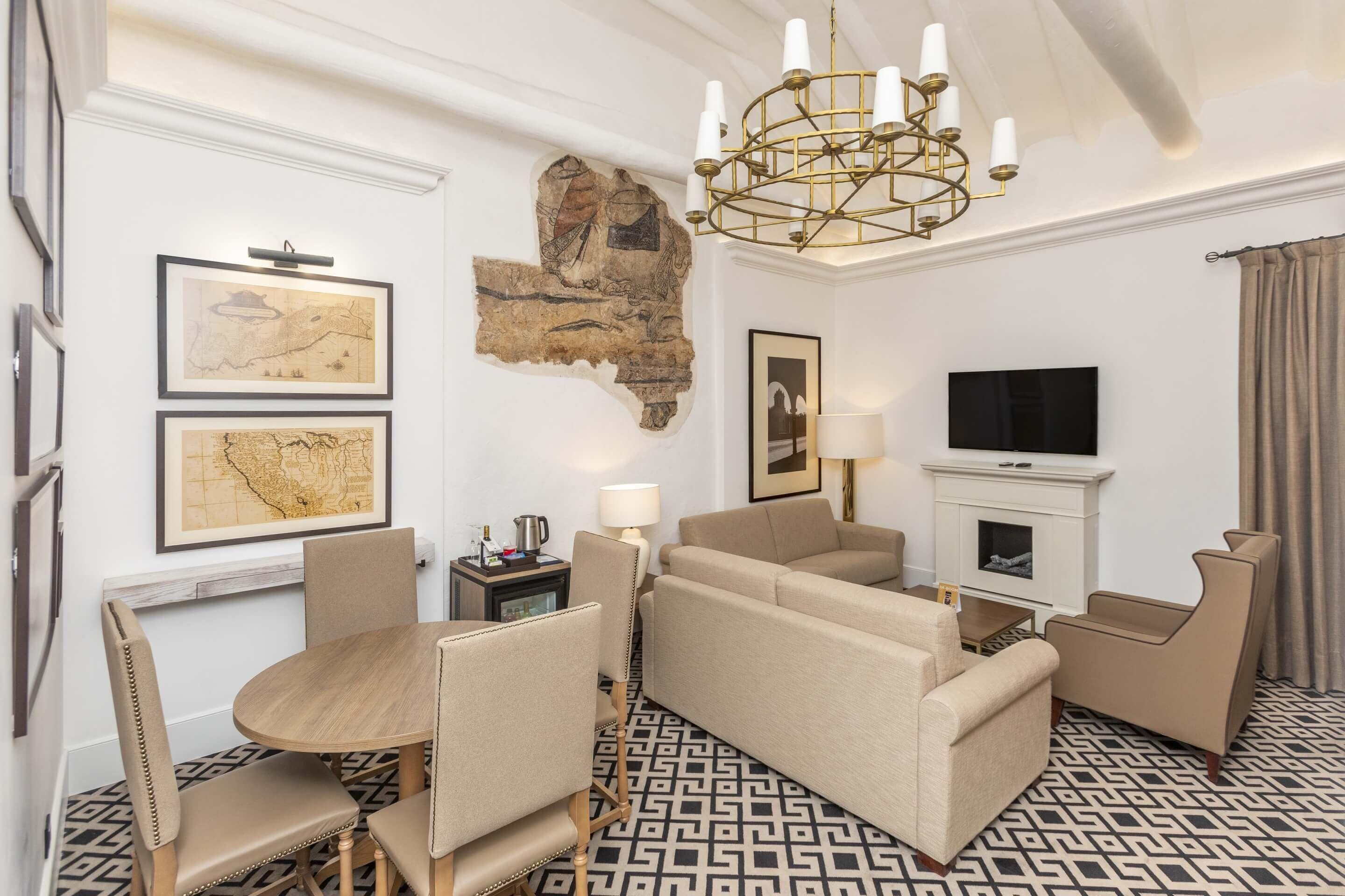 A modern living room with a sofa set, a dining table with chairs, a chandelier, and a television.