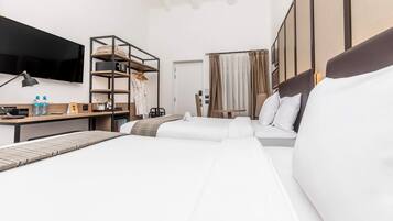 A modern hotel room with a large bed, a desk with a lamp, a TV mounted on the wall, and a wardrobe.