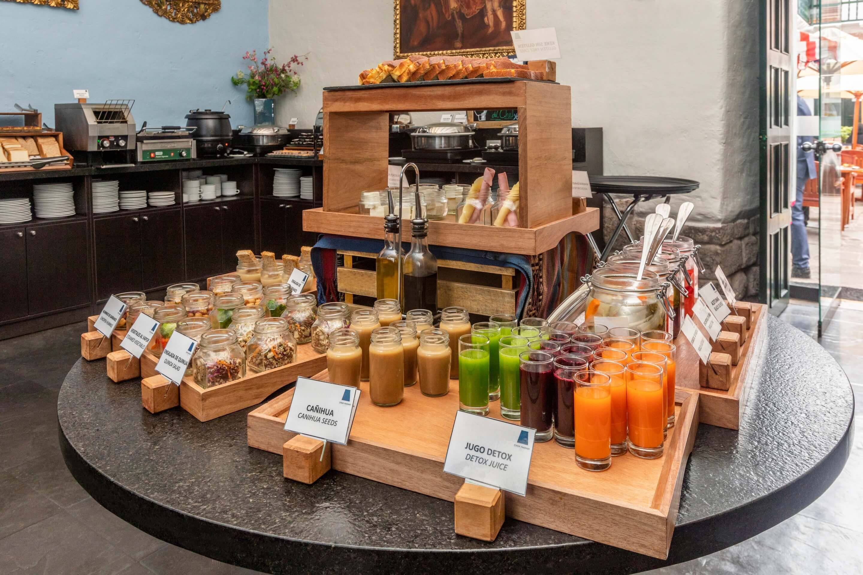 A buffet setup with various food items and beverages, including jars of granola, smoothies, and juices.