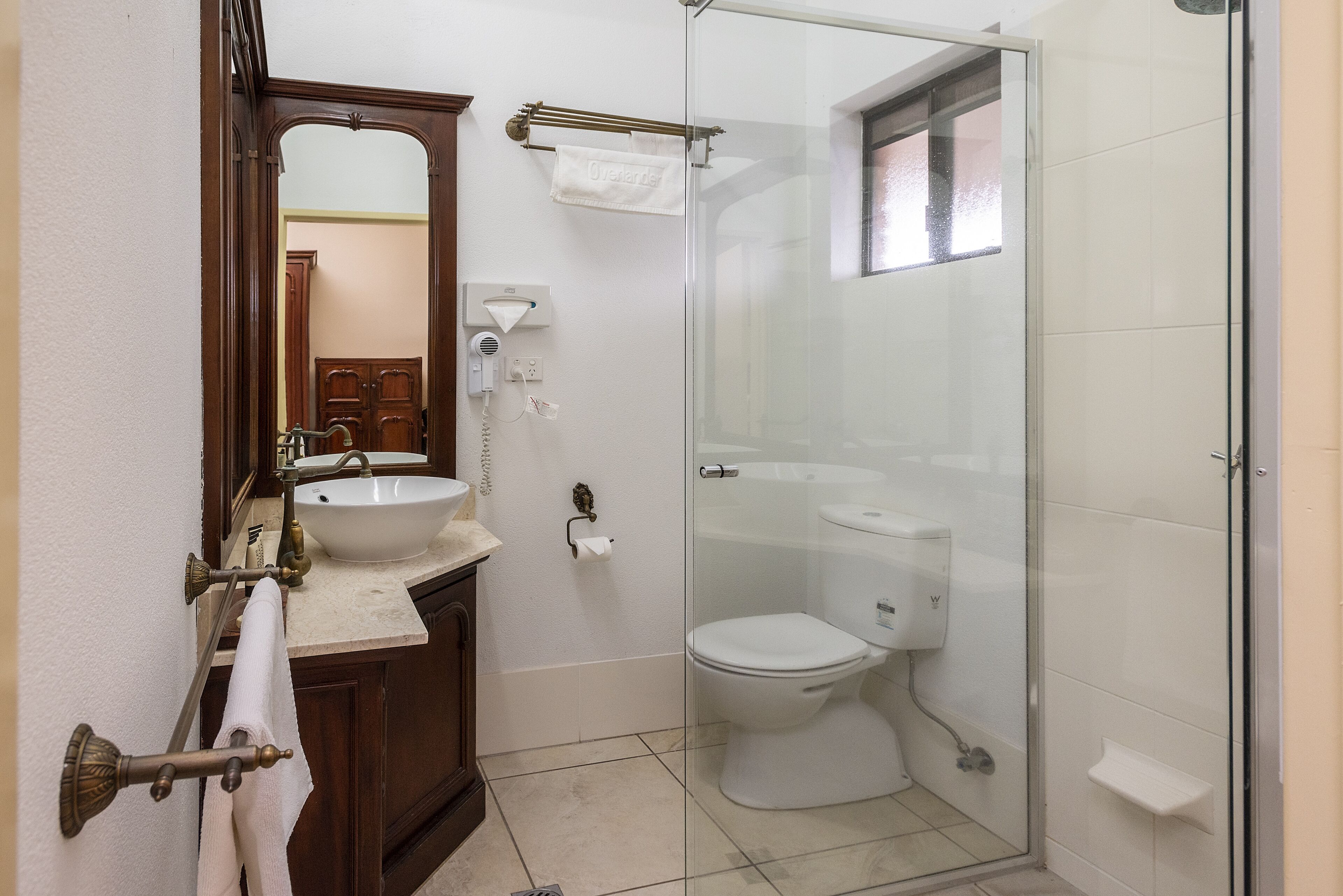 Un baño con ducha de vidrio, un lavamanos con espejo y un inodoro.