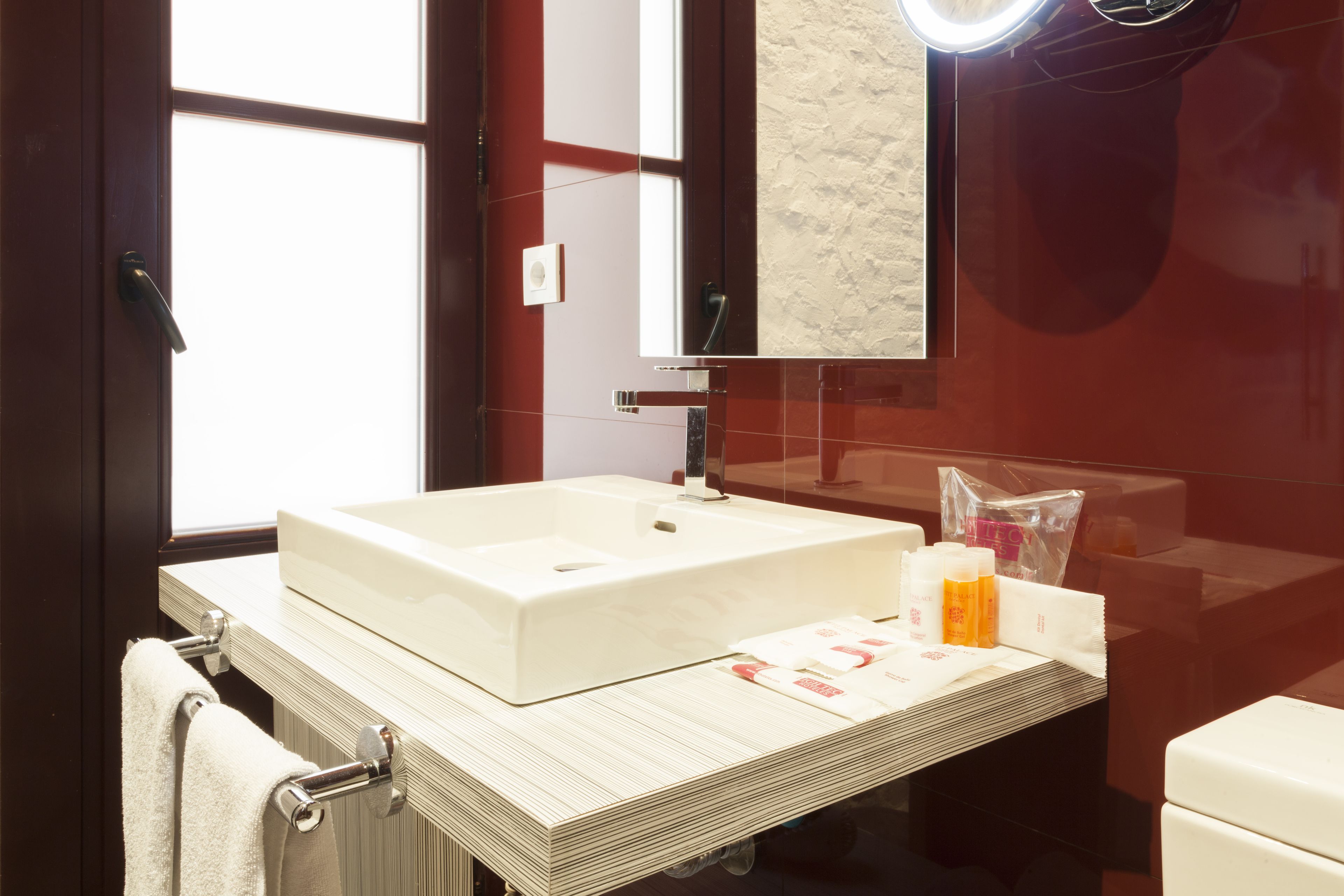 Un baño moderno con un lavamanos grande de color blanco, un espejo y un toallero.