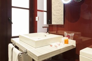 A modern bathroom with a large white sink, a mirror, and a towel rack.
