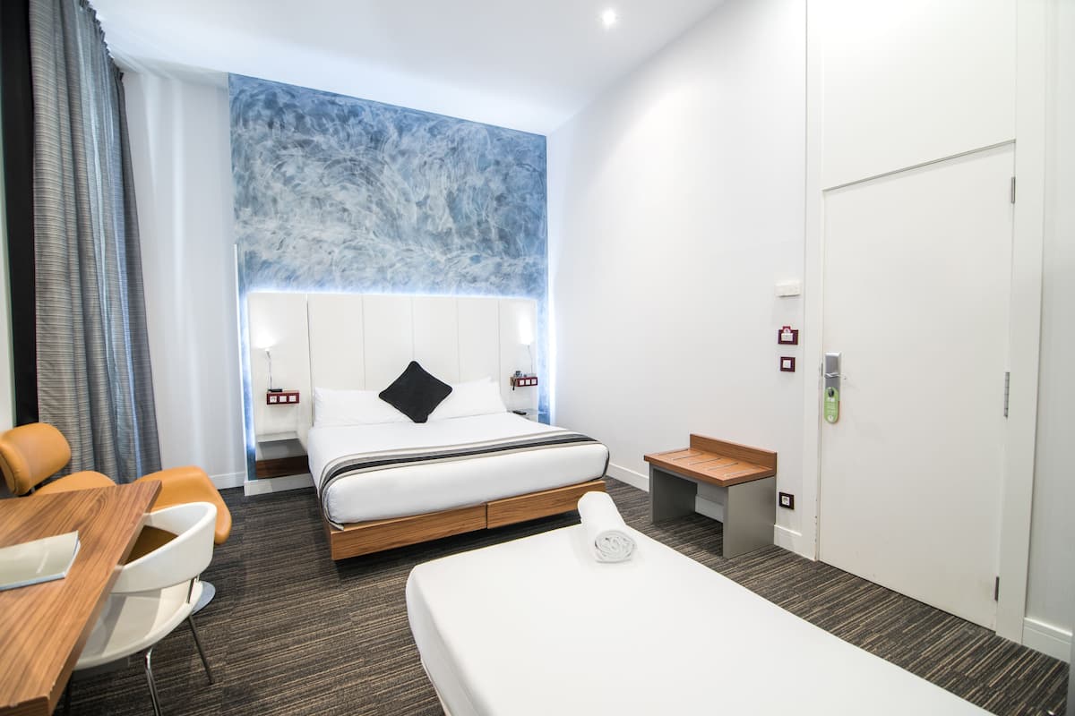 Una habitación de hotel moderna con una cama grande, un escritorio y una zona de estar.