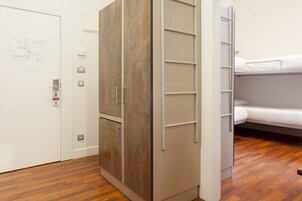 Una habitación con un armario de madera, una cama litera y una puerta con un mapa.