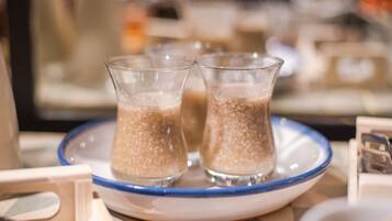 Trois verres contenant une boisson, posés sur une assiette à bordure bleue, l’ensemble étant placé sur une table recouverte d’une nappe à motifs.
