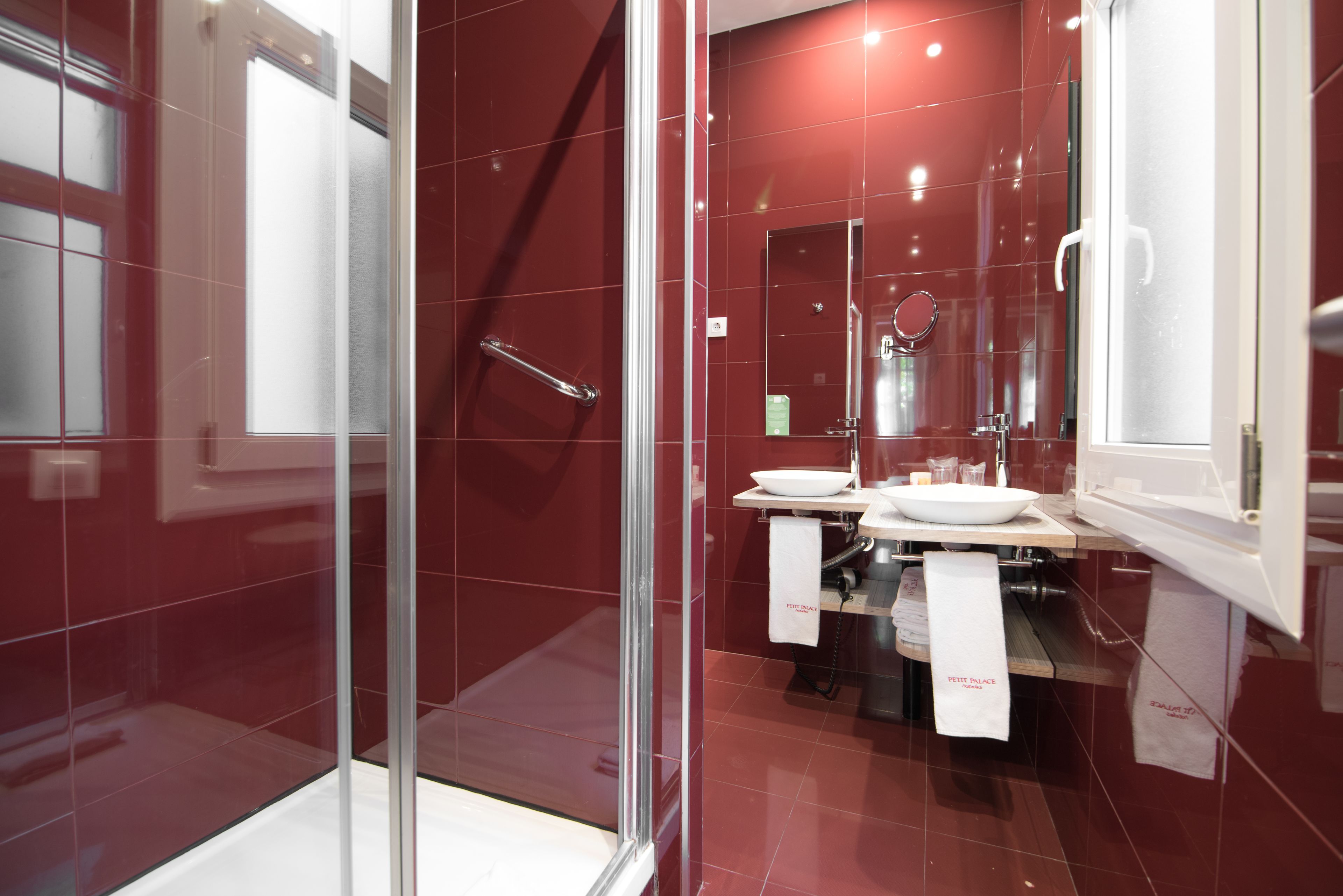 A modern bathroom with a glass shower enclosure, a vanity with a sink and mirror, and a towel rack with a white towel.