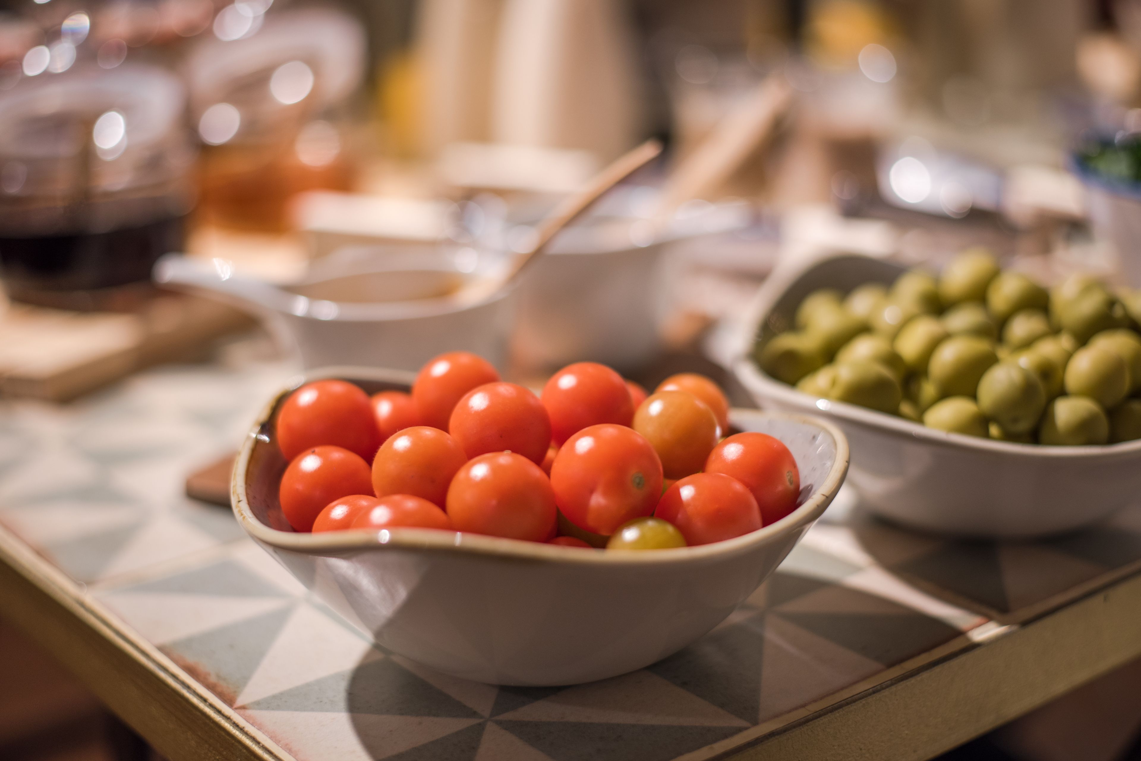 A table with a bowl of cherry tomatoes and a bowl of olives.