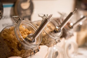 A close-up of glass jars with metal lids, likely containing food items, arranged on a table.