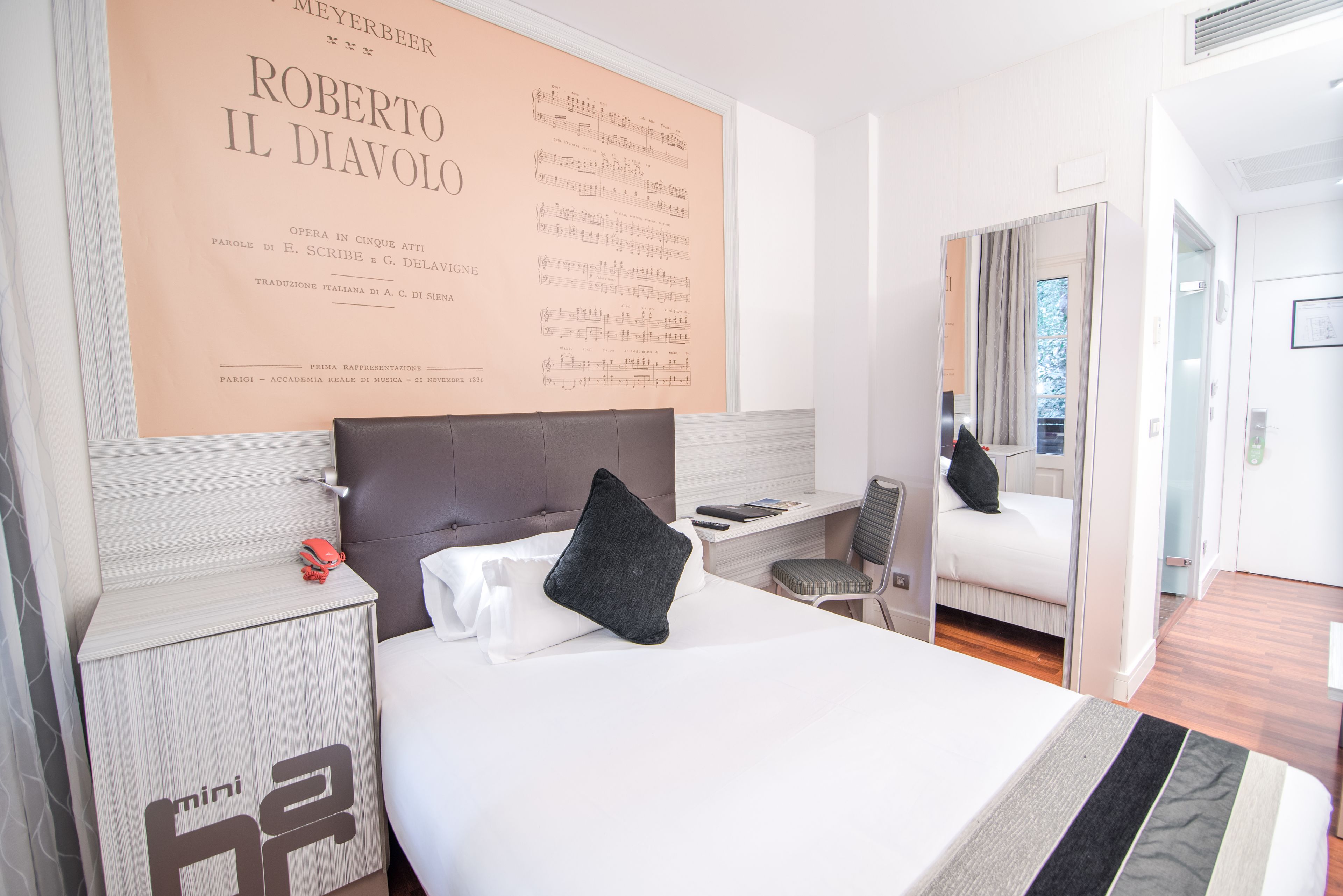 Ein modernes Hotelzimmer mit einem großen Bett, einem Schreibtisch und einem Spiegel.