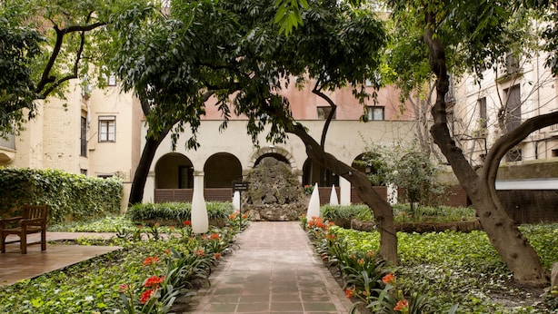 Un patio con un sendero de piedra, arcos y abundante vegetación.
