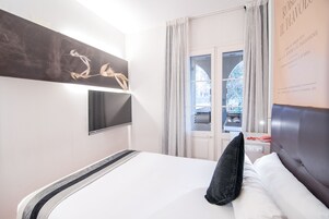 Quarto de hotel com cama, televisão de tela plana na parede e janela com cortinas.