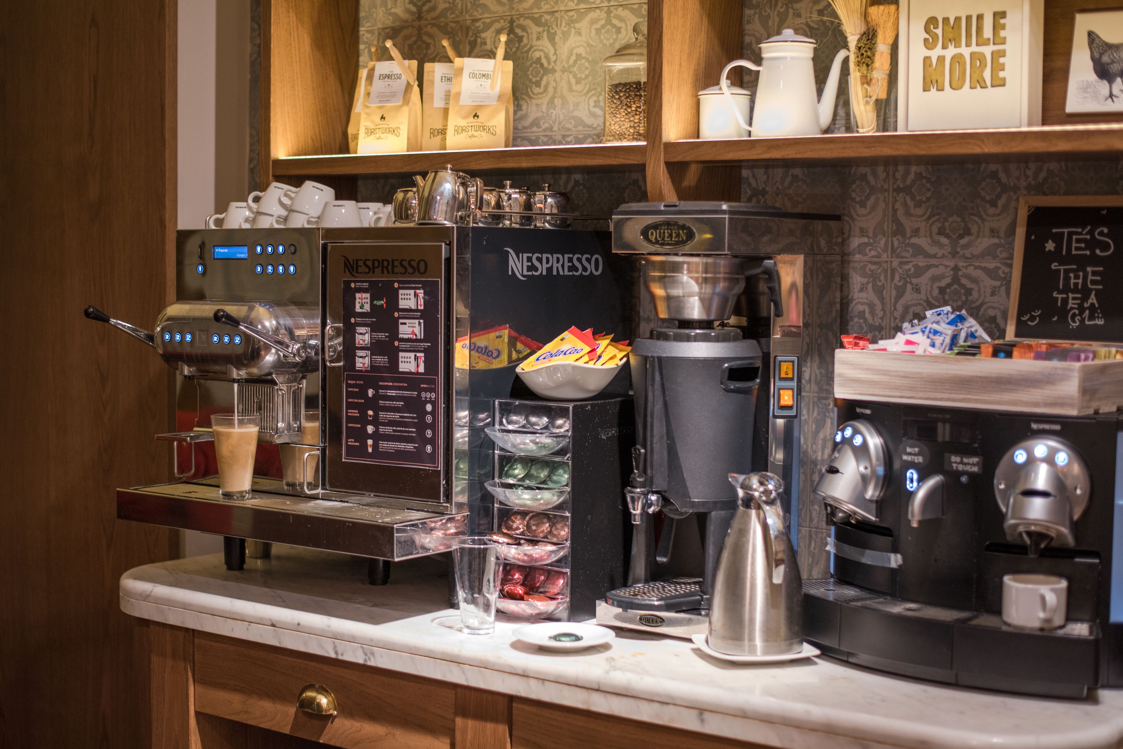 Een koffiehoek met meerdere espresso machines, een koffiemolen en diverse koffiecups.